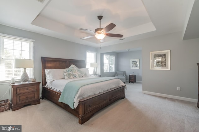 bedroom featuring light colored carpet, a raised ceiling, visible vents, and baseboards