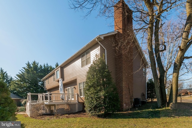 exterior space featuring a yard, a chimney, central AC, and a wooden deck