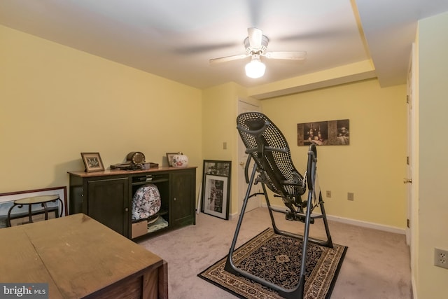 exercise area with a ceiling fan, light colored carpet, and baseboards