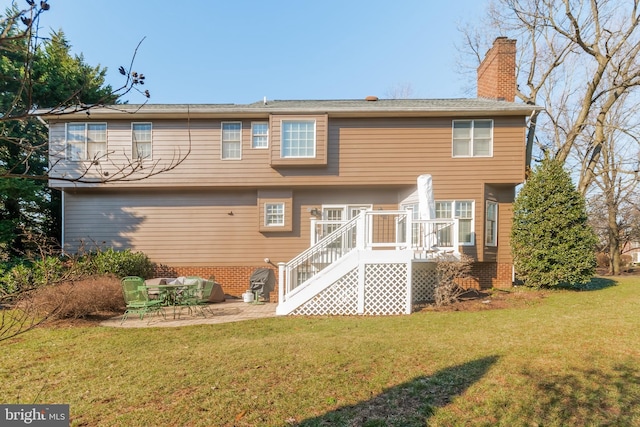 back of property featuring a lawn, a chimney, stairway, a wooden deck, and a patio area