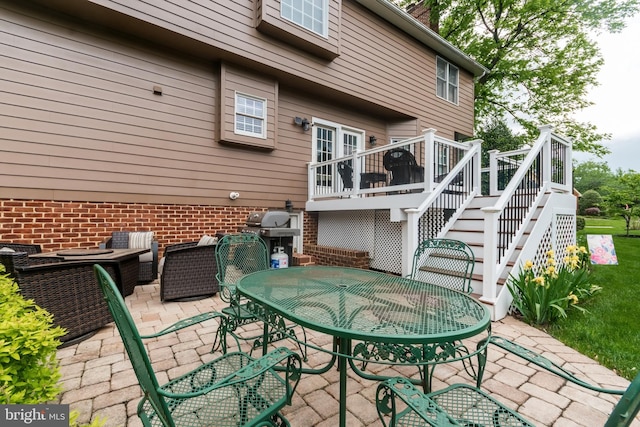 view of patio with stairs, a wooden deck, and outdoor dining area