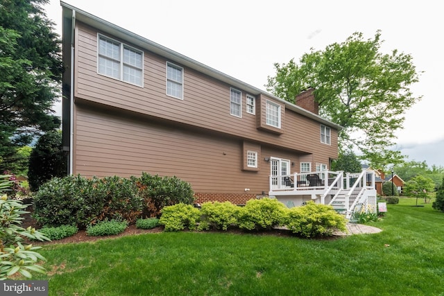 rear view of property featuring a chimney, a deck, a yard, and stairs