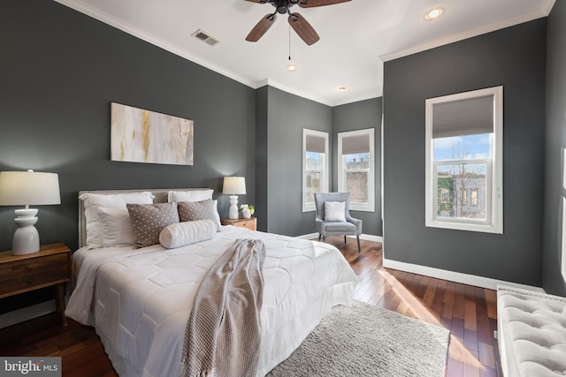 bedroom with ceiling fan, wood finished floors, visible vents, baseboards, and ornamental molding