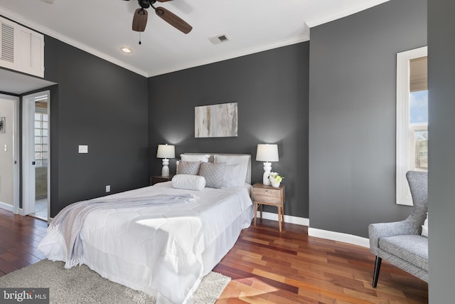 bedroom with baseboards, visible vents, crown molding, and wood finished floors