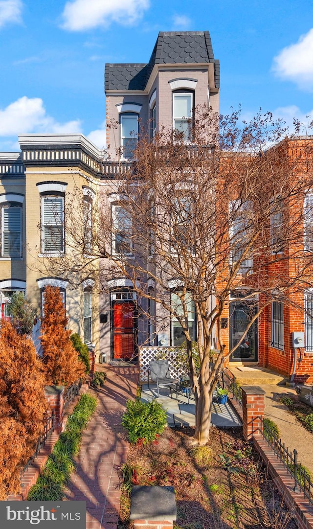 view of front of property with mansard roof and brick siding