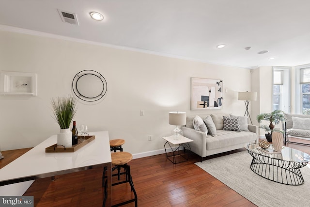 living area featuring baseboards, visible vents, dark wood finished floors, and crown molding