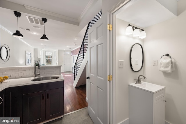 bathroom with ornamental molding, visible vents, a sink, and decorative backsplash