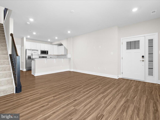 unfurnished living room featuring stairs, wood finished floors, visible vents, and recessed lighting