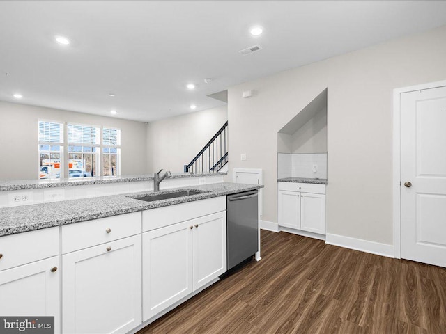 kitchen featuring stainless steel dishwasher, light stone counters, white cabinets, and a sink