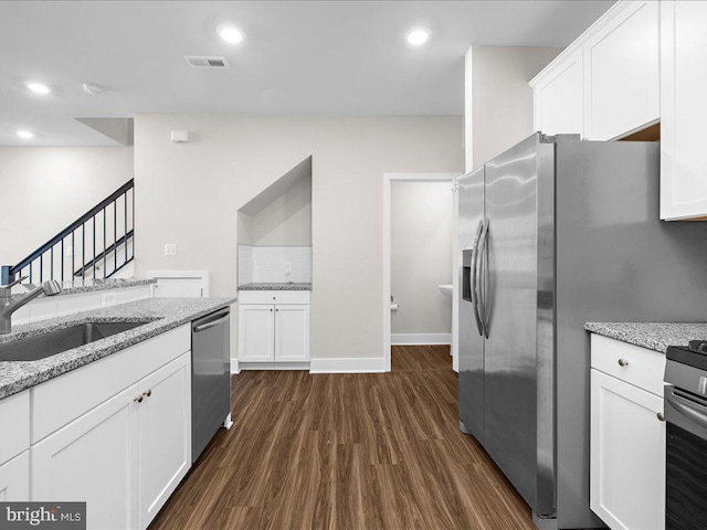 kitchen with white cabinets, light stone counters, stainless steel appliances, and a sink