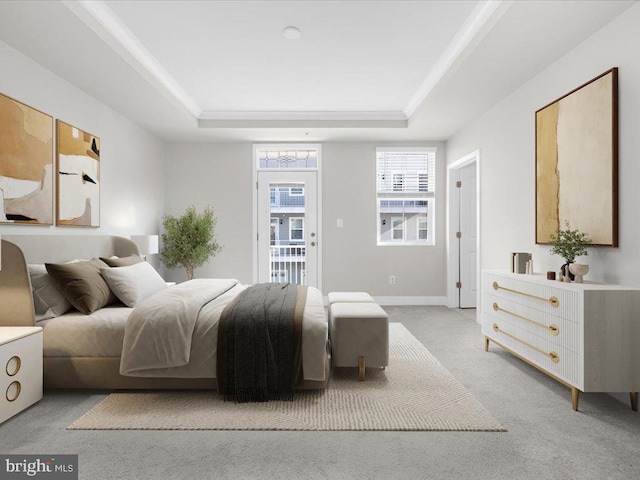 bedroom with light carpet, a tray ceiling, baseboards, and access to exterior