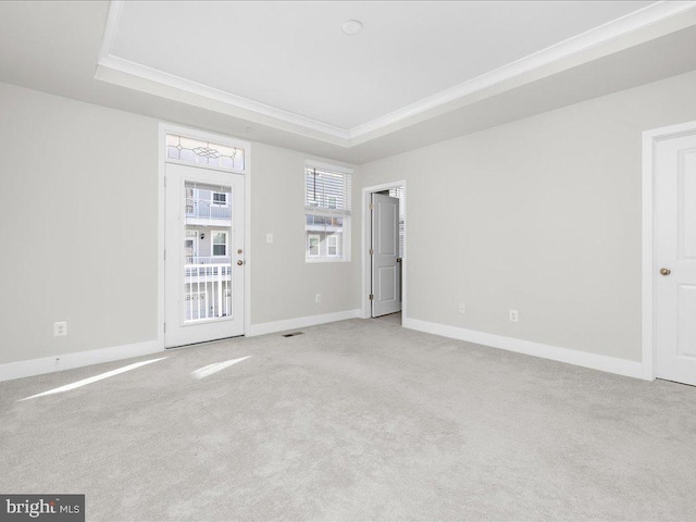 spare room with a tray ceiling, light carpet, and baseboards