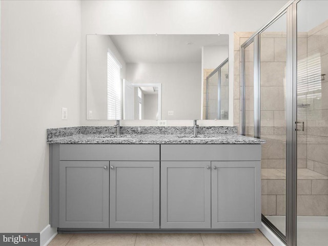 full bathroom with a sink, double vanity, and a shower stall