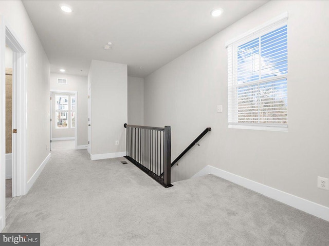 corridor featuring light carpet, visible vents, an upstairs landing, and baseboards