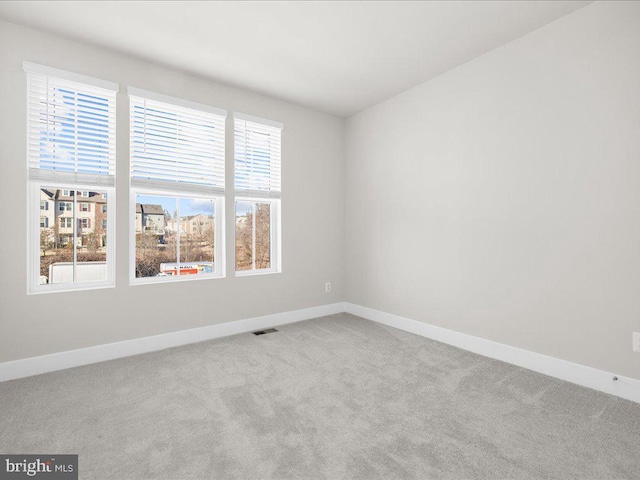 carpeted spare room with baseboards and visible vents