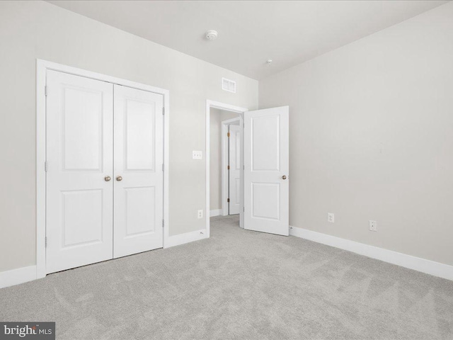 unfurnished bedroom with light colored carpet, a closet, visible vents, and baseboards