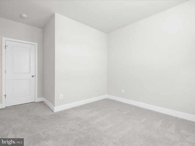 unfurnished room featuring baseboards and light colored carpet