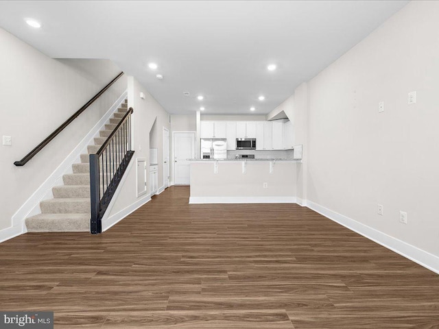 unfurnished living room with stairs, baseboards, dark wood finished floors, and recessed lighting