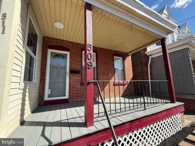 property entrance featuring covered porch and brick siding