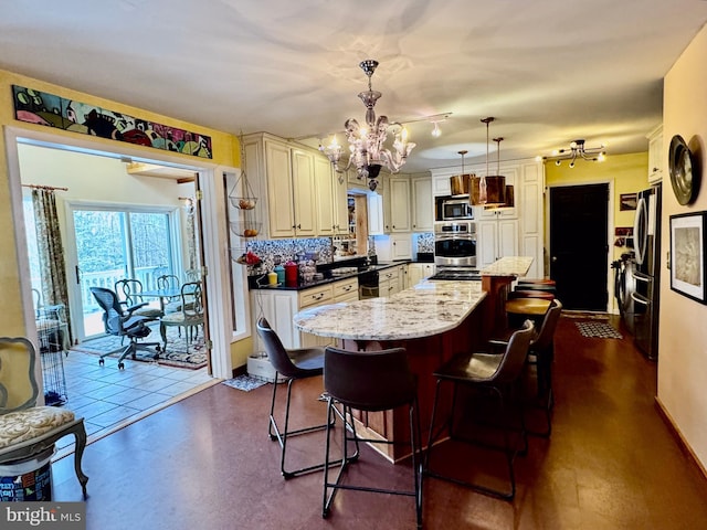 kitchen featuring a center island, stainless steel appliances, hanging light fixtures, a chandelier, and a kitchen breakfast bar