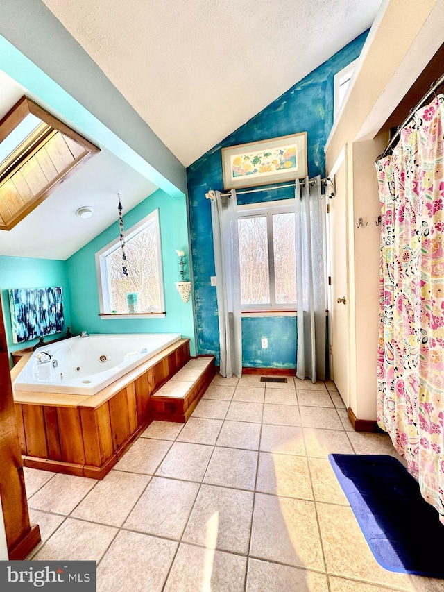 bathroom featuring visible vents, lofted ceiling with skylight, a textured ceiling, tile patterned flooring, and a whirlpool tub