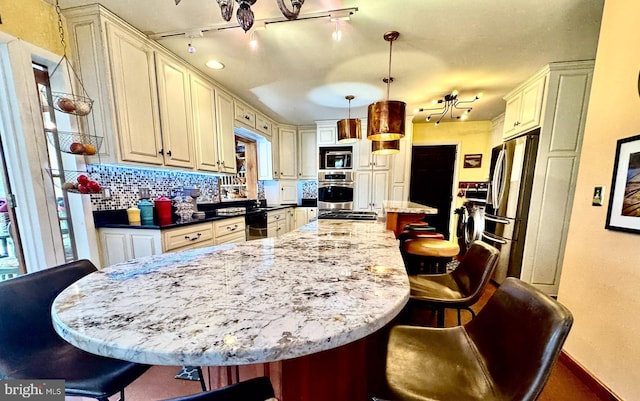 kitchen featuring cream cabinets, stainless steel appliances, a breakfast bar, and decorative light fixtures