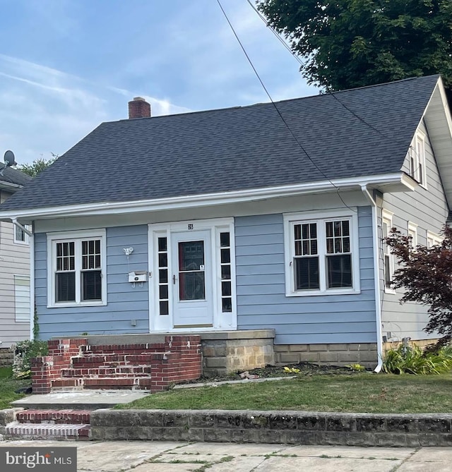 view of front facade with a chimney and roof with shingles