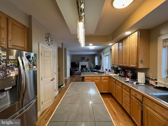 kitchen with light wood-style floors, stainless steel fridge, and tile countertops