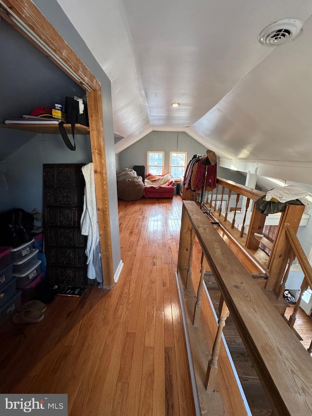 additional living space with lofted ceiling, hardwood / wood-style flooring, stairs, and visible vents