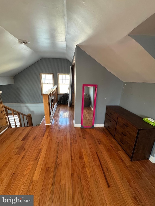 additional living space with vaulted ceiling, wood finished floors, and baseboards