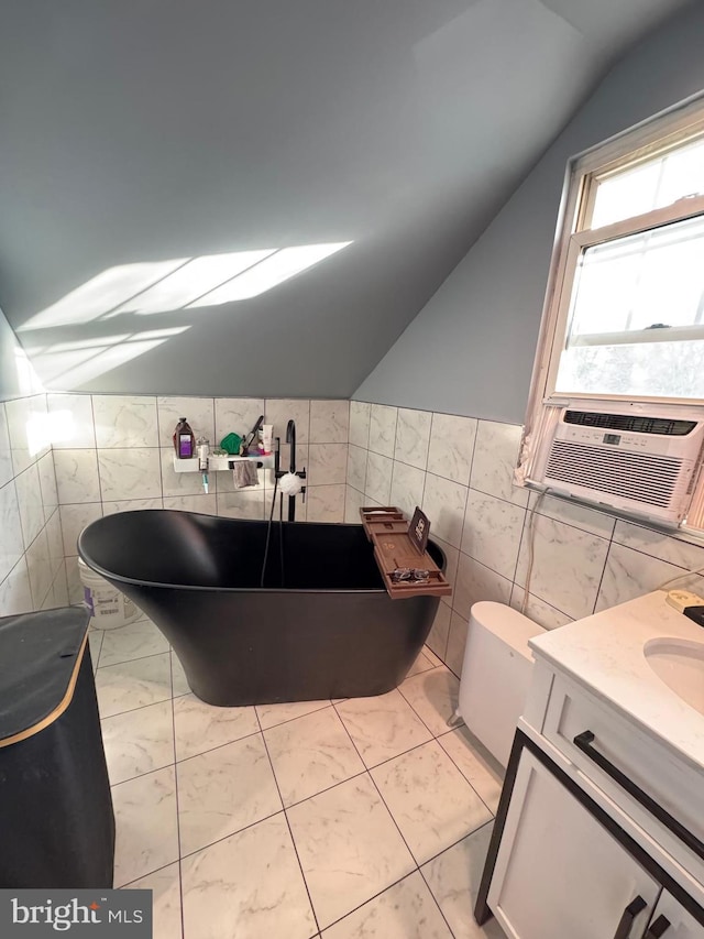 bathroom with lofted ceiling, a soaking tub, cooling unit, vanity, and tile walls