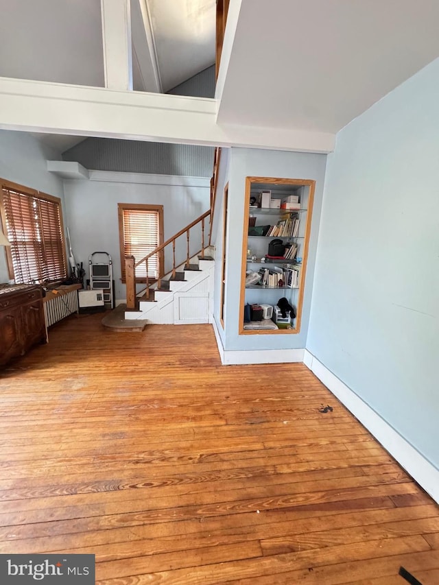 interior space with built in shelves, stairway, wood finished floors, and baseboards