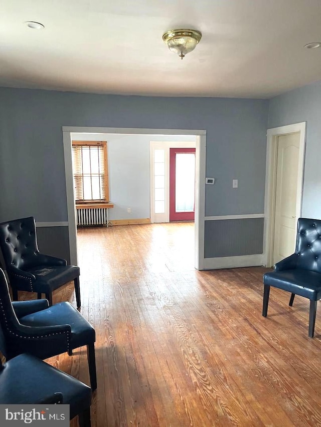 sitting room featuring radiator, wood-type flooring, and baseboards