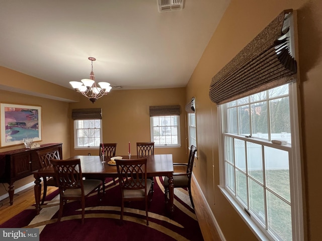 dining room featuring baseboards, visible vents, a notable chandelier, and wood finished floors