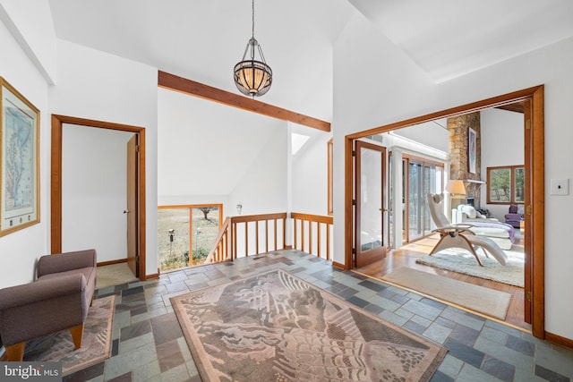 foyer entrance featuring baseboards, high vaulted ceiling, stone tile flooring, and beamed ceiling