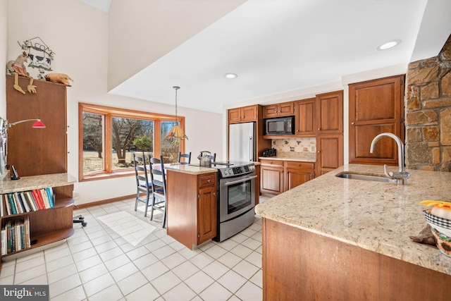 kitchen with appliances with stainless steel finishes, hanging light fixtures, a sink, and light stone countertops