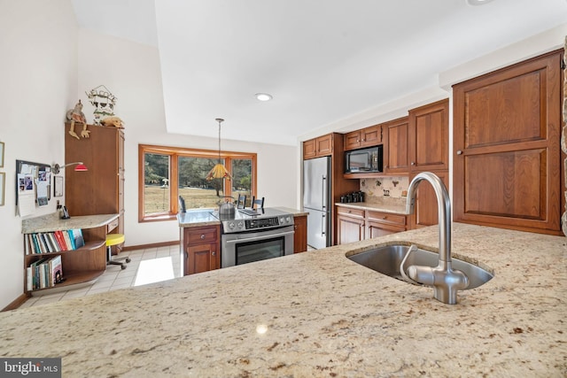 kitchen featuring appliances with stainless steel finishes, pendant lighting, brown cabinetry, and a sink