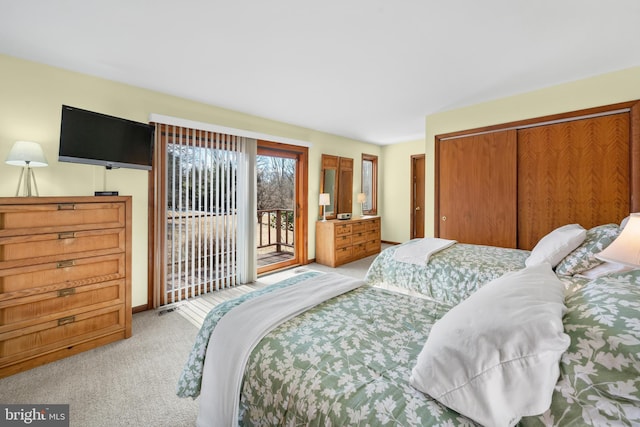 bedroom with a closet, light colored carpet, and access to exterior