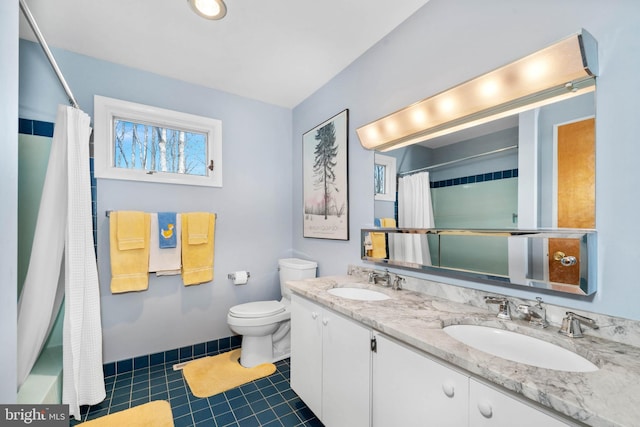 full bathroom with toilet, tile patterned flooring, double vanity, and a sink