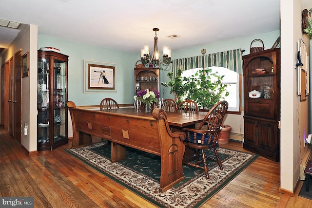 dining area with a baseboard radiator, visible vents, a notable chandelier, and wood finished floors