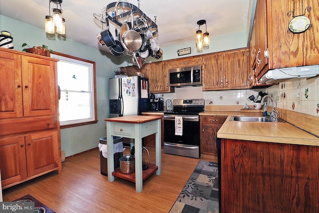 kitchen featuring stainless steel appliances, a sink, light wood-style flooring, and tasteful backsplash