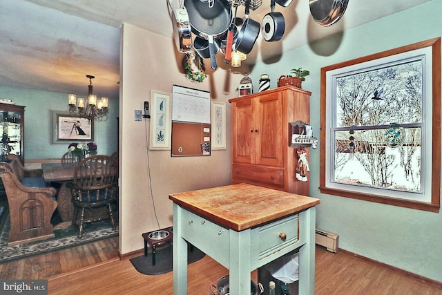 kitchen featuring a notable chandelier, a baseboard heating unit, wood finished floors, baseboards, and hanging light fixtures