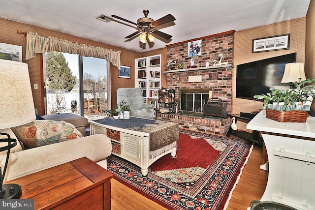 living area featuring visible vents, a fireplace, wallpapered walls, and wood finished floors