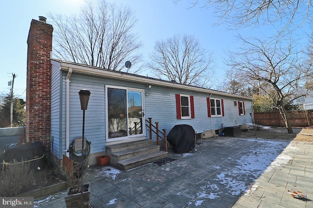 rear view of house with a patio, a chimney, entry steps, fence, and cooling unit