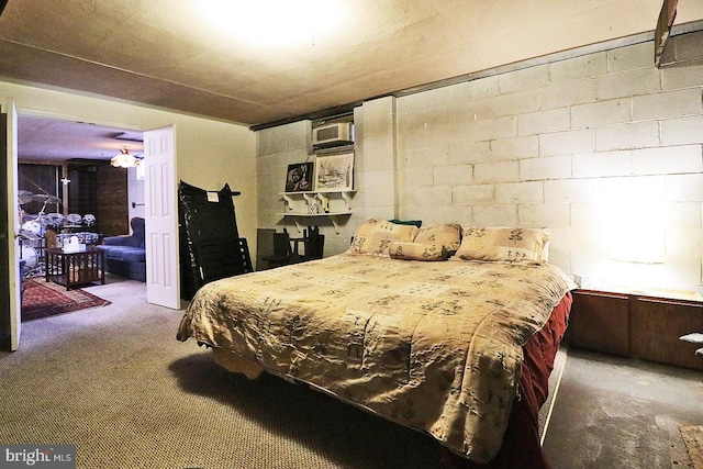 bedroom with concrete block wall, carpet, and a wall mounted AC