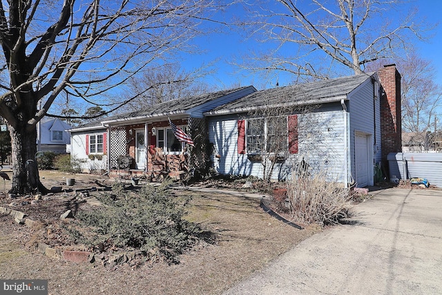 view of front of house with driveway, a chimney, and an attached garage