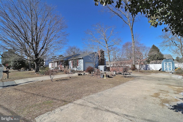 view of front of property with a garage, an outbuilding, concrete driveway, and a storage shed