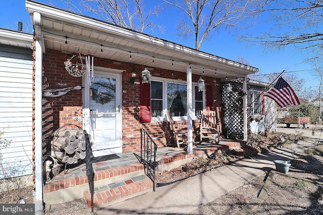 entrance to property with covered porch and brick siding