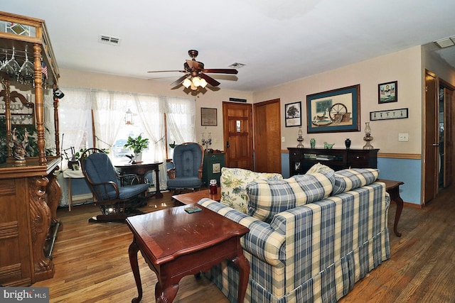 living area with visible vents, dark wood finished floors, and ceiling fan