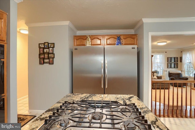 kitchen featuring crown molding, baseboards, appliances with stainless steel finishes, and light stone countertops